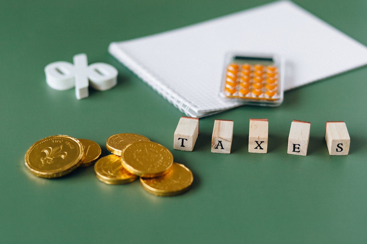 Close-up of tax-related items including coins, calculator, and word taxes on a green background.